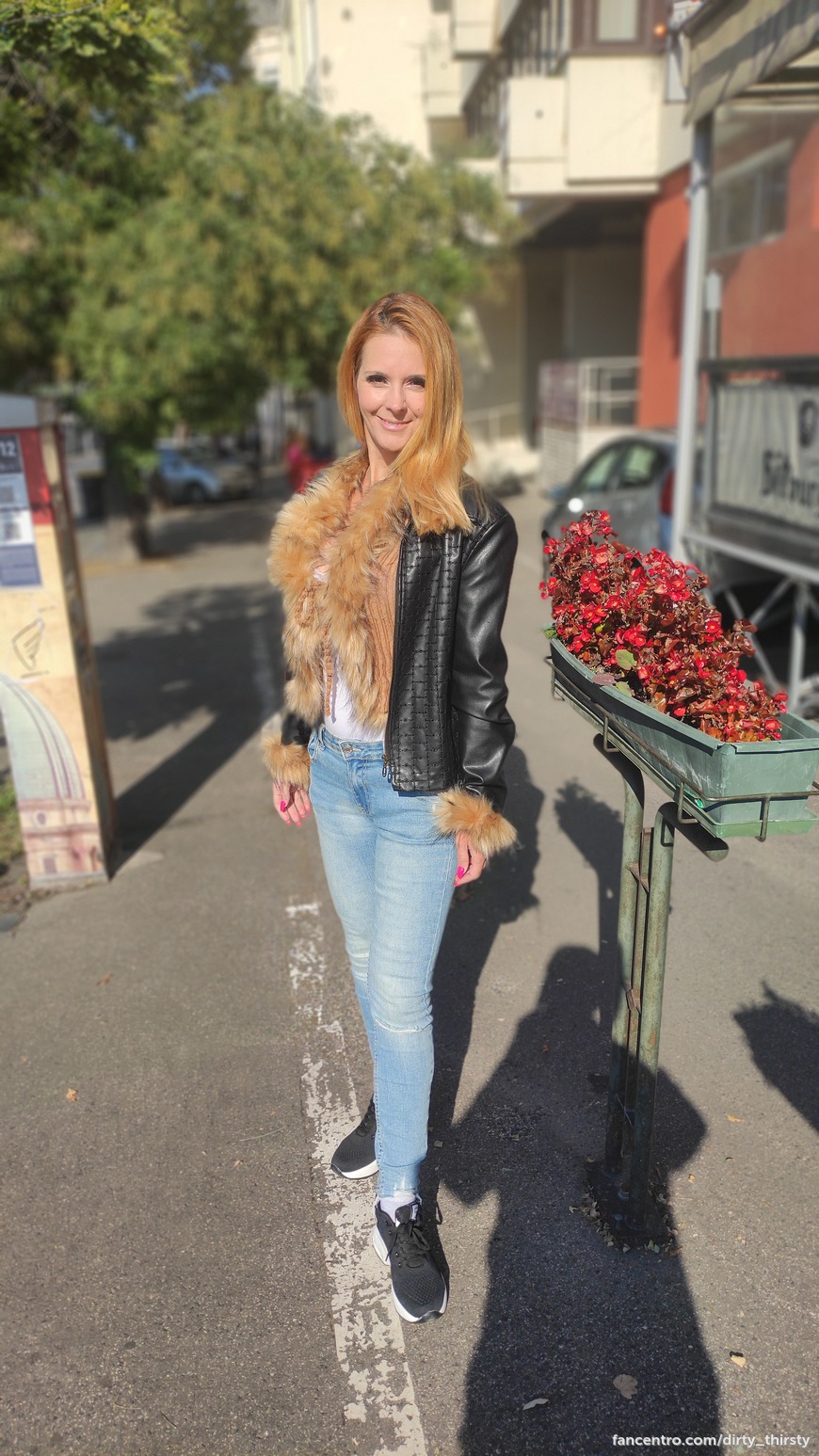 On the street in a black leather jacket and fur. 1